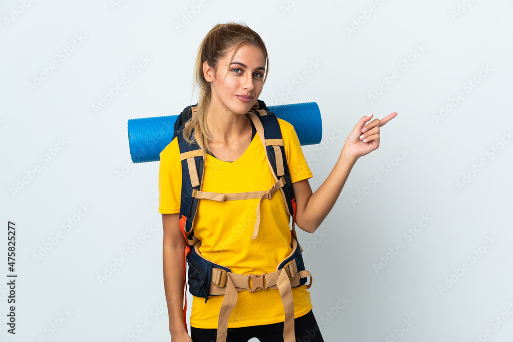 Young mountaineer woman with a big backpack isolated on white background pointing finger to the side Young mountaineer woman with a big backpack isolated on white background pointing finger to the side