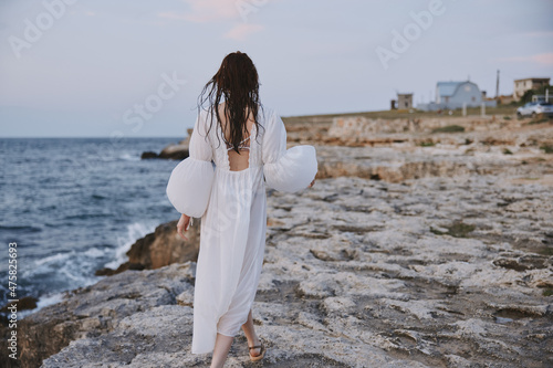 Woman walking in white dress on stone beach © SHOTPRIME STUDIO
