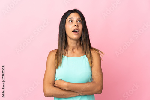 Caucasian girl isolated on pink background looking up and with surprised expression