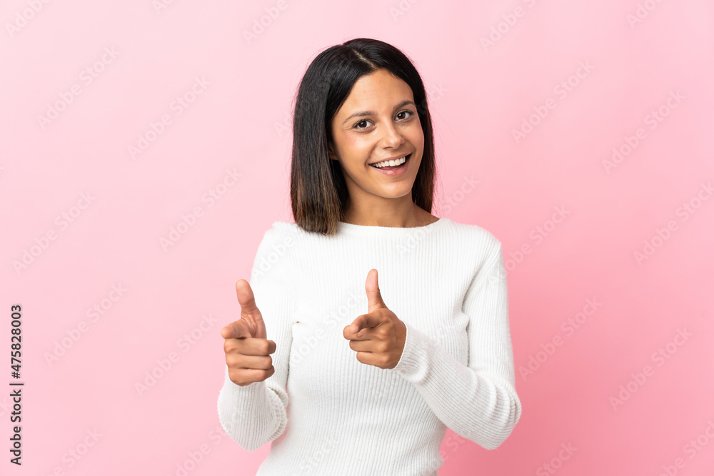 Caucasian girl isolated on pink background pointing to the front and smiling