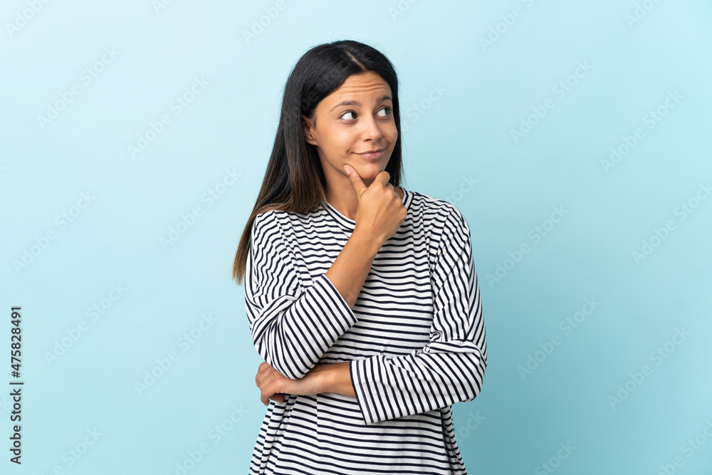 Caucasian girl isolated on blue background thinking an idea while looking up Caucasian girl isolated on blue background thinking an idea while looking up