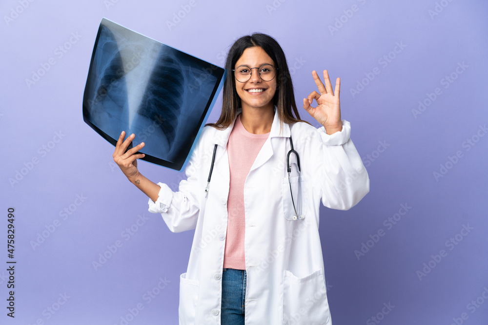 Young doctor woman holding a radiography showing ok sign with fingers Young doctor woman holding a radiography showing ok sign with fingers