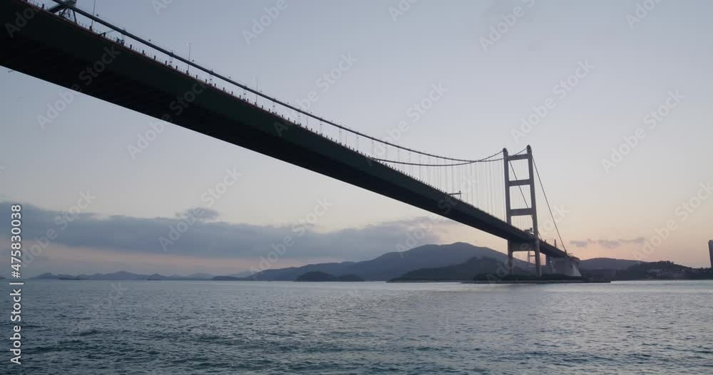 Take boat cross the harbor with Tsing Ma bridge in Hong Kong at sunset time