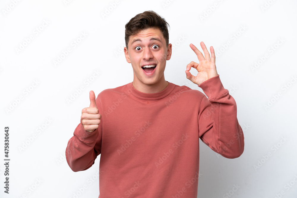 Young handsome Brazilian man isolated on white background showing ok sign and thumb up gesture Young handsome Brazilian man isolated on white background showing ok sign and thumb up gesture