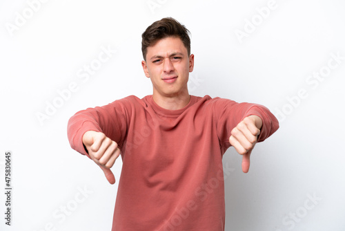 Young handsome Brazilian man isolated on white background showing thumb down with two hands