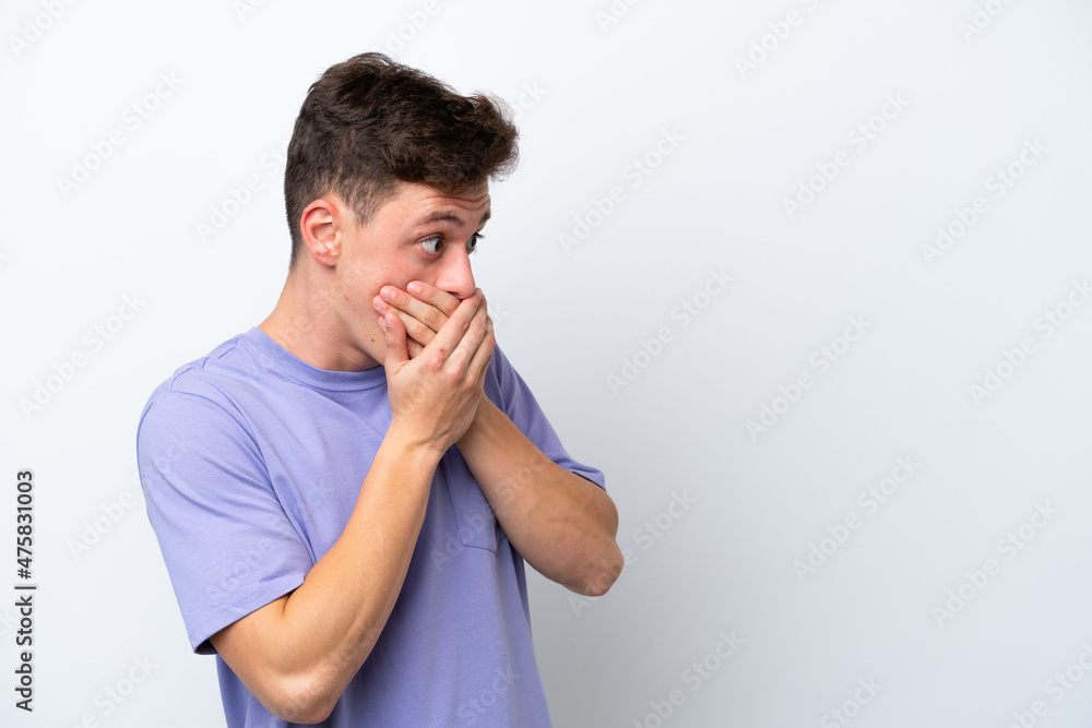 Young handsome Brazilian man isolated on white background covering mouth and looking to the side Young handsome Brazilian man isolated on white background covering mouth and looking to the side