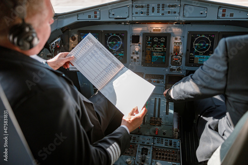 Vászonkép Aircraft pilot studying documents before the flight in cockpit