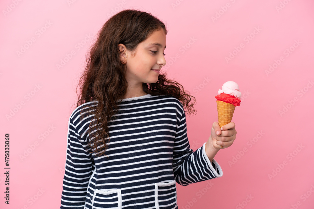 Little caucasian girl holding an ice cream isolated on pink background looking to the side Little caucasian girl holding an ice cream isolated on pink background looking to the side