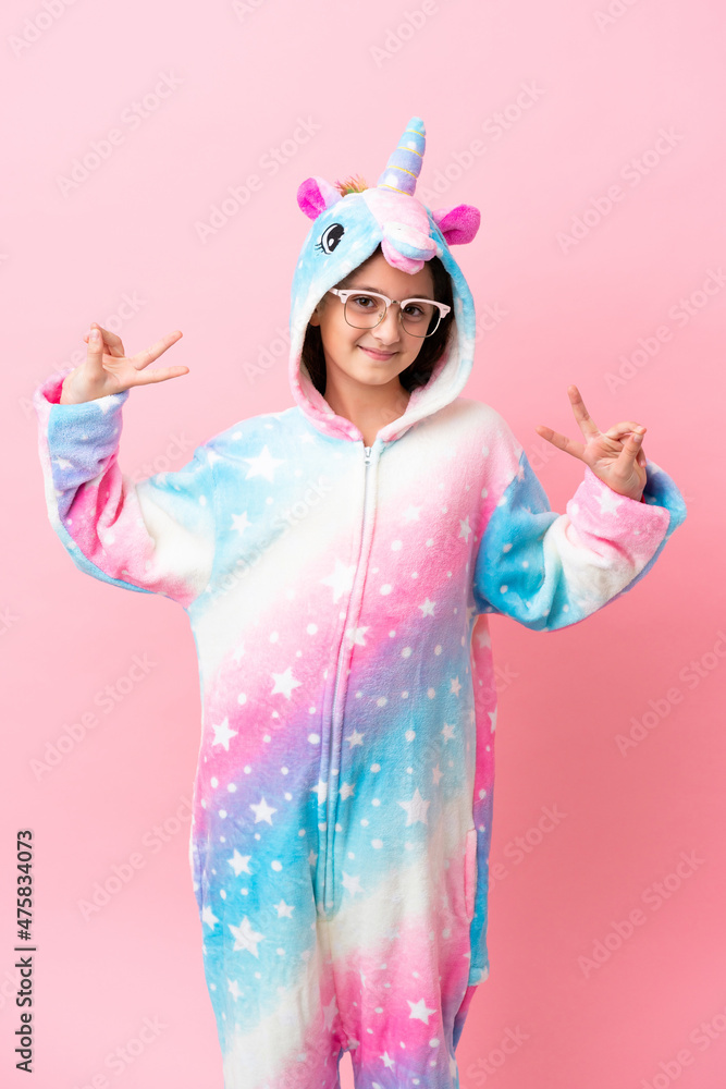 Little caucasian woman wearing a unicorn pajama isolated on pink background Little caucasian woman wearing a unicorn pajama isolated on pink background