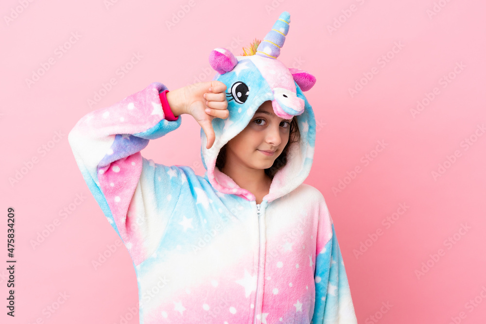Little caucasian woman wearing a unicorn pajama isolated on pink background showing thumb down with negative expression Little caucasian woman wearing a unicorn pajama isolated on pink background showing thumb down with negative expression