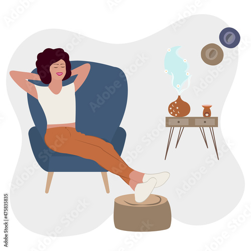 Aromatherapy Concept.. Young woman relaxes on the armchair while enjoying the aromatherapy from oil diffuser with flower smell. 