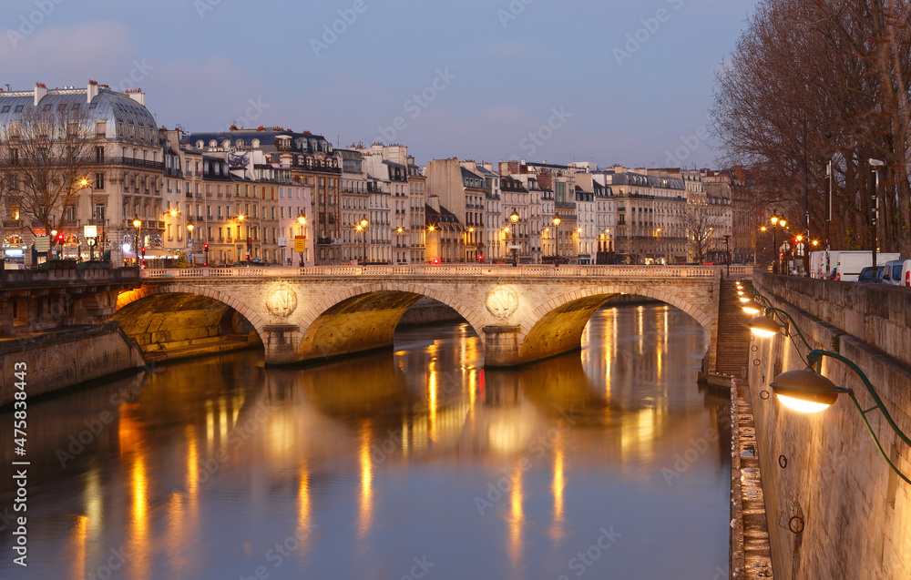 Stone bridge Pont au Change in Paris at the dusk. On the left are towers of Conciergerie, on right northern bank of river Seine. Paris.