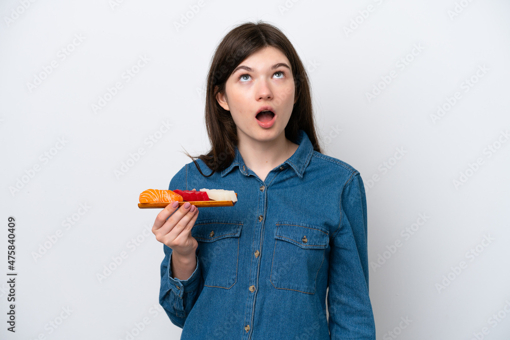 Young Russian woman holding sashimi isolated on white background looking up and with surprised expression Young Russian woman holding sashimi isolated on white background looking up and with surprised expression