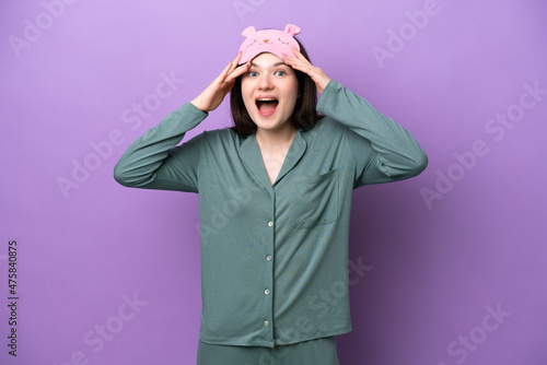 Young Russian woman in pajamas isolated on purple background with surprise expression © luismolinero