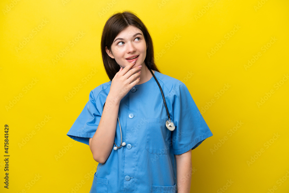Young surgeon doctor Russian woman isolated on yellow background looking up while smiling Young surgeon doctor Russian woman isolated on yellow background looking up while smiling