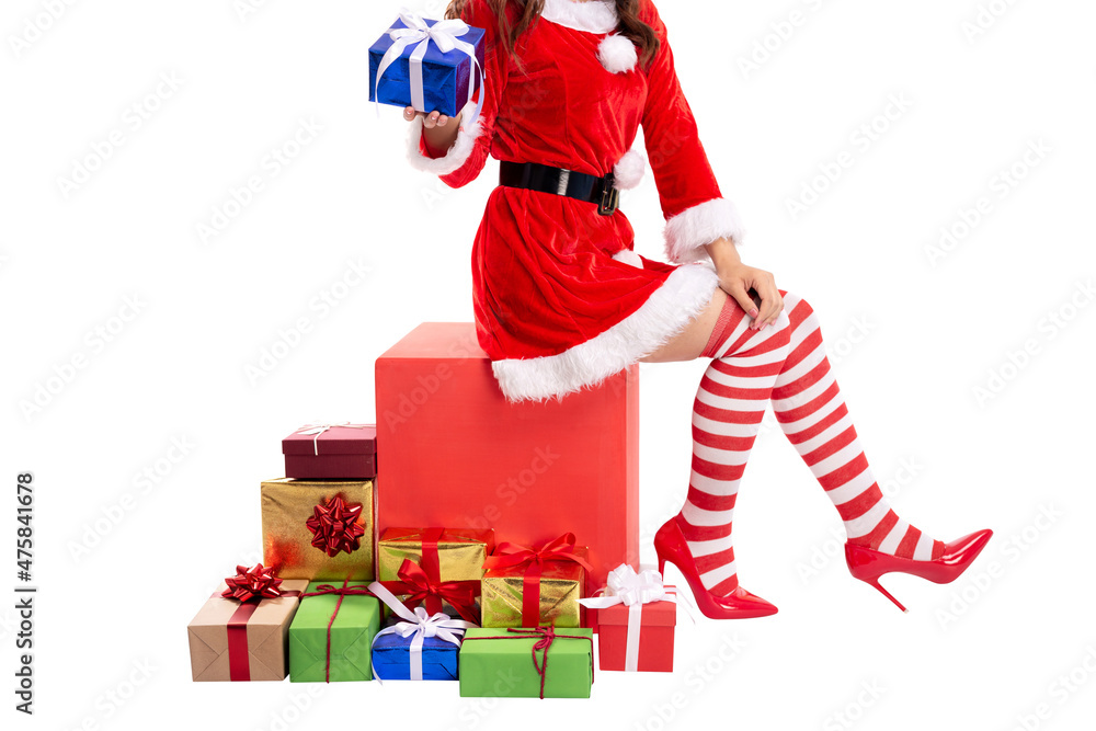 Cropped image of woman in red santa claus outfit sitting on red box with holding christmas gift. Santa girl with gift boxes on floor isolated on white background.