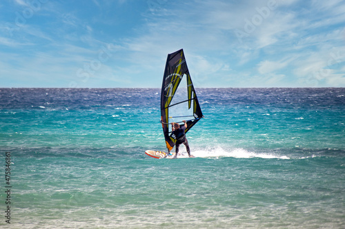 Wind surfer with black yellow transparent sails at Atlantic beach Risco del Paso in east of Fuerteventura
