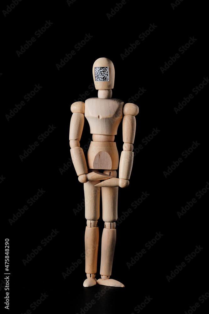 Wooden mannequin with a QR code on a dark background. Selective focus. The concept of the trend of assigning QR codes to people in connection with countering the new Covid virus infection. Wooden mannequin with a QR code on a dark background. Selective focus. The concept of the trend of assigning QR codes to people in connection with countering the new Covid virus infection.