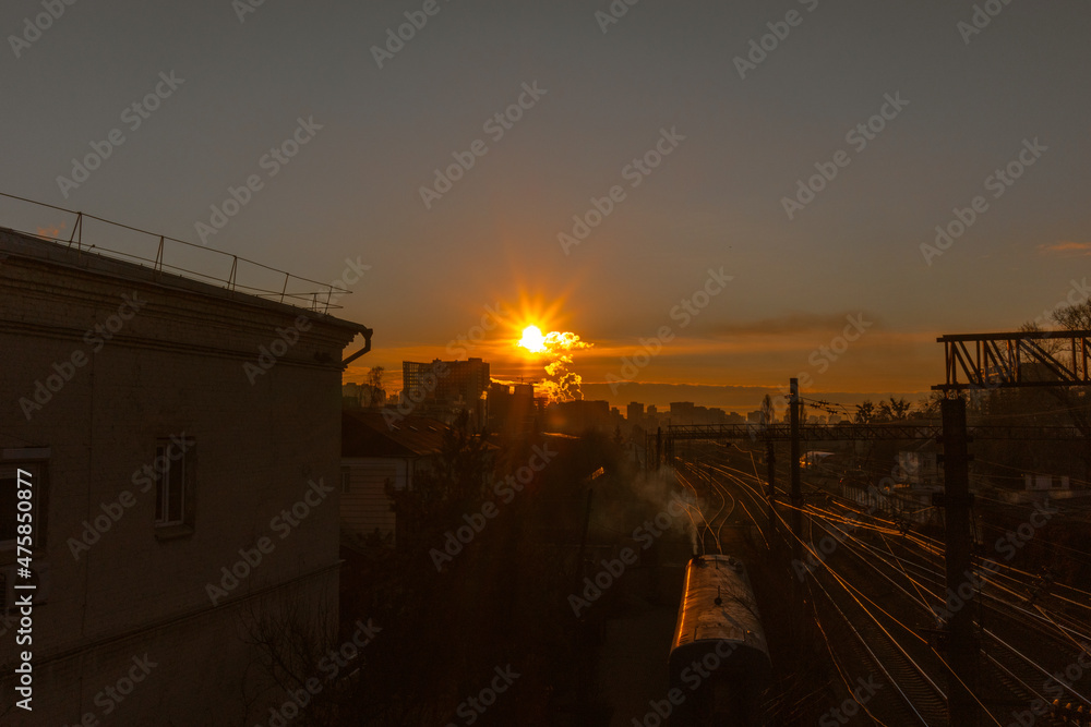 Dawn over the railroad. The rising sun over the houses near the railroad tracks