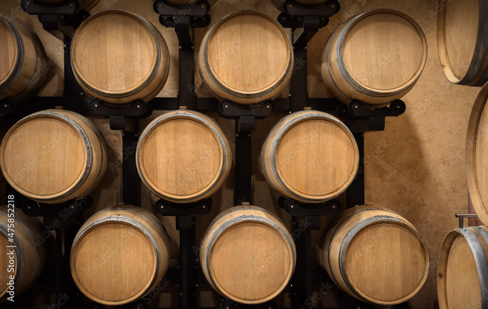 Wine storage, wooden wine barrels in a row in winery cellar Wine storage, wooden wine barrels in a row in winery cellar