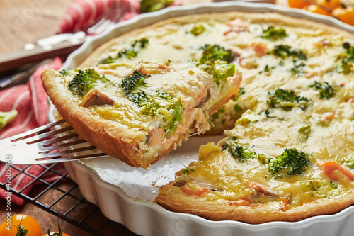 Homemade quiche with red fish, salmon, broccoli and cheese on wooden background