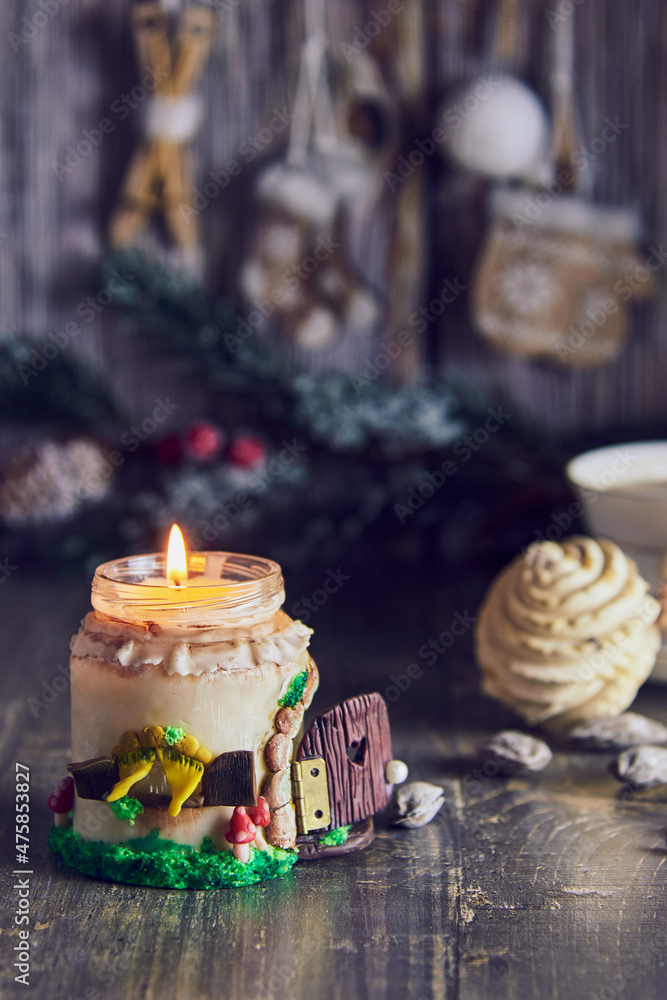 A burning handmade candle on the background of Christmas decor .