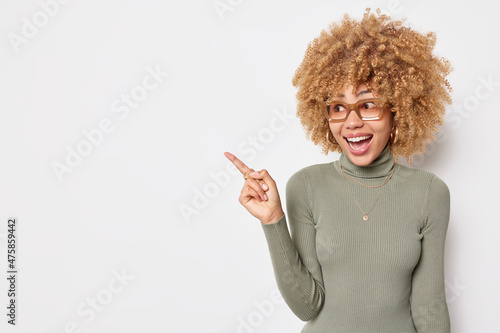 Bild auf Leinwand Happy surprised female promoter points away at blank copy space shows something