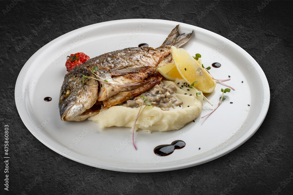 Dorado with mashed potatoes and creamy mushroom sauce. Isolated on a black background. Dorado with mashed potatoes and creamy mushroom sauce. Isolated on a black background.