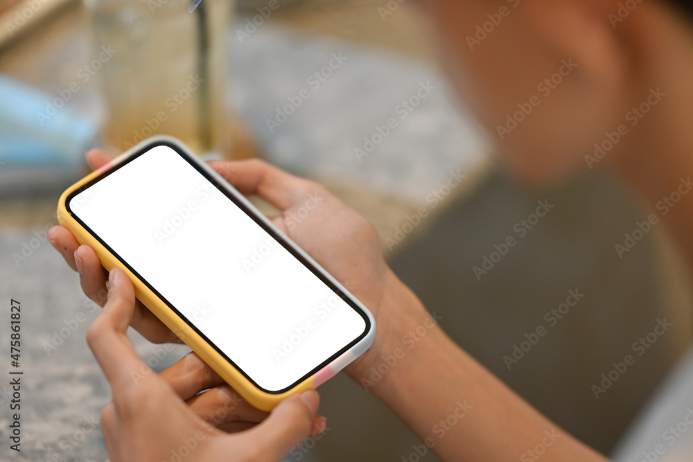 Photo of a young man using a white blank screen smartphone at the table.