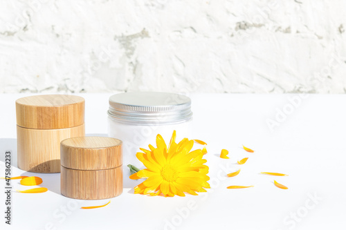 Set of cosmetics. Natural cosmetic. Bamboo jars, glass jar with cream. Calendula. Light background.