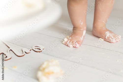 Baby feet in cream from cake stand on white background