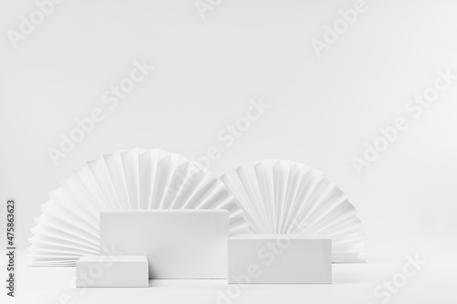 Set of three rectangle white podiums mockup with oriental paper fans as decor in modern minimal style  stage for presentation of cosmetic product or goods  advertising  design  copy space  front view.