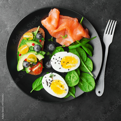 Delicious breakfast, tapas, appetizer. Bread, vegetables, herbs, spinach, eggs, salmon, berries, blueberries. Top view