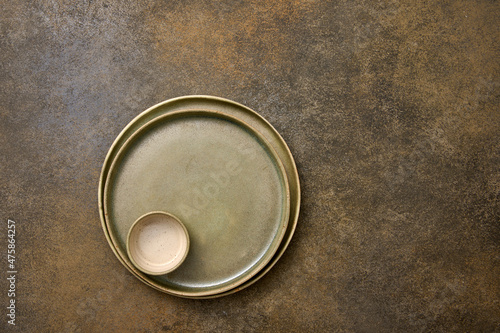 Empty green ceramic two plates and saucepan one in one on rustic background, copy space, top view