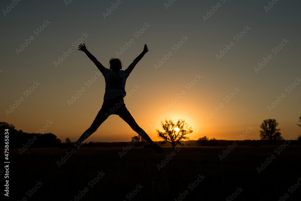 silhouette of a woman jumping up at sunset up