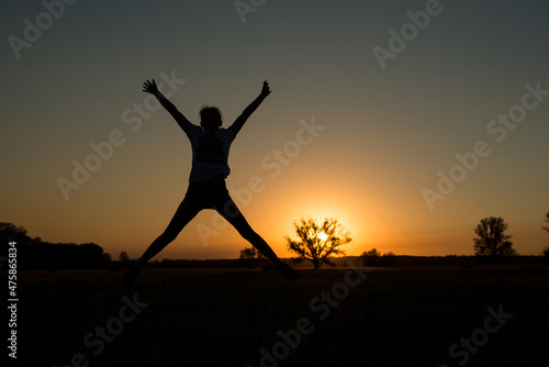 silhouette of a woman jumping up at sunset up