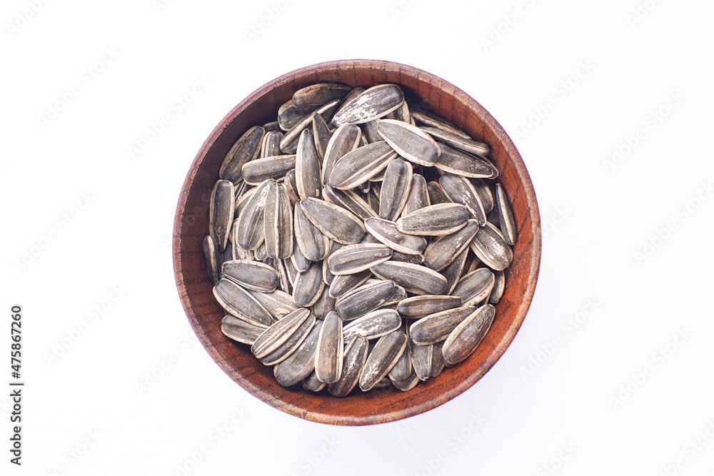 Sunflower seeds in a wooden bowl on a white table Sunflower seeds in a wooden bowl on a white table