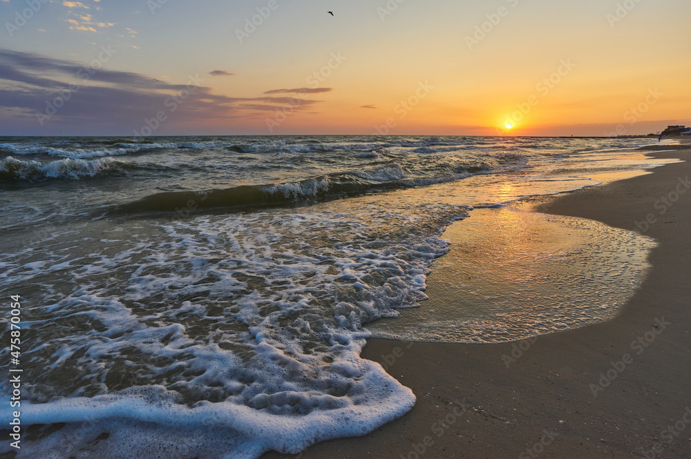 Soft sea waves and bubbles on the beach with sunset sky