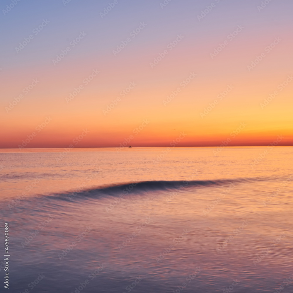 Vivid sunset sky and motion blur of the sea under with long exposure effect.