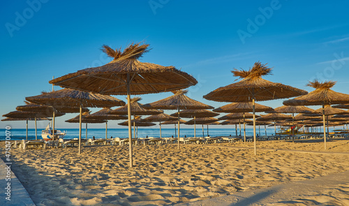 Thatched beach umbrellas and loungers on a beach at an idyllic tropical resort