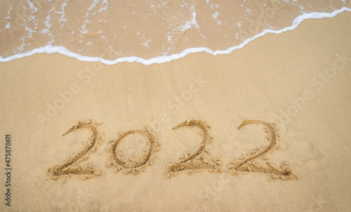 2022 year message handwritten in sand on beautiful beach background. New Years concept.