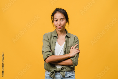 Portrait of young Asia lady with positive expression, arms crossed, smile broadly, dressed in casual clothing and looking at camera over yellow background. Happy adorable glad woman rejoices success.