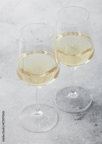 Two glasses of white homemade summer refreshing wine on light background.