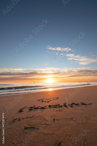 A beautiful sunset on the beach of Mazagon, Spain. In the sand written the word Huelva, Spanish province.