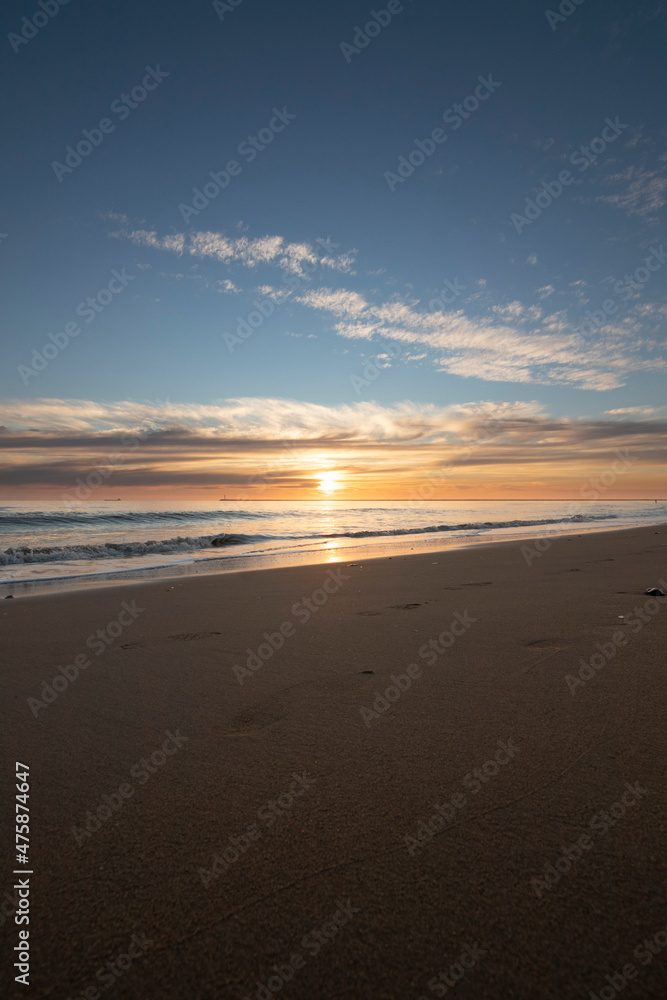A beautiful sunset on the beach of Mazagon, Spain. In the background the silhouettes of two surfers.