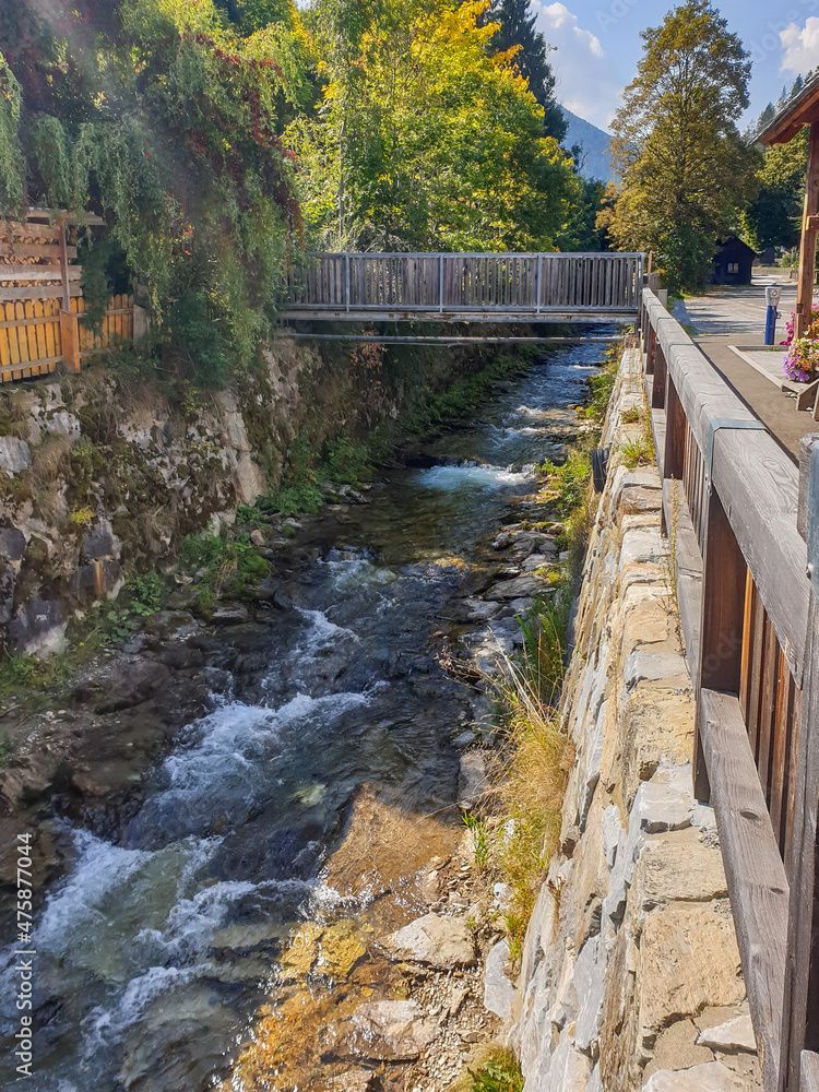 Fototapeta premium Kleiner Bachlauf in einem Dorf mit Brücke