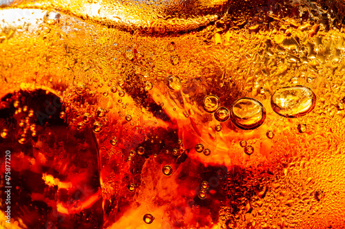 Close up view of the ice cubes in dark cola background. Texture of cooling sweet summer's drink with foam and macro bubbles on the glass wall. Fizzing or floating up to top of surface