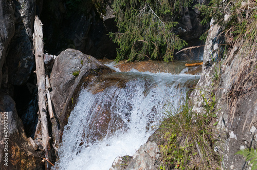 kleiner Wasserfall in bergiger und waldiger Landschaft an einem sonnigen Herbsttag © lucky  photographer