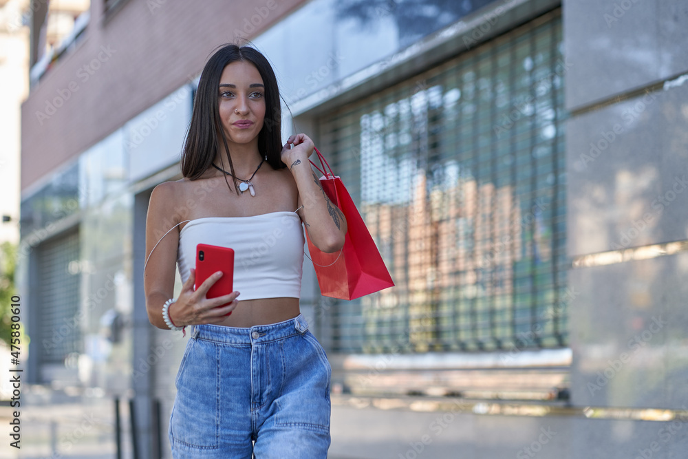young girl with shopping bags and smartphone looking away