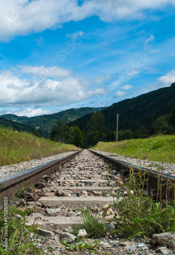 Der Weg ins Irgendwo. Perspektivischer Blick von Bahnschienen, die scheinbar in einen Wald führen.